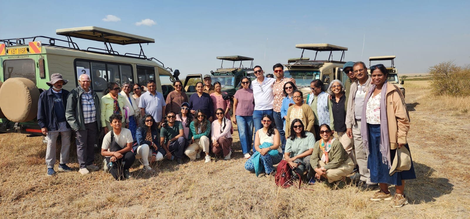 Safari group gathered in front of open-roof safari vehicles